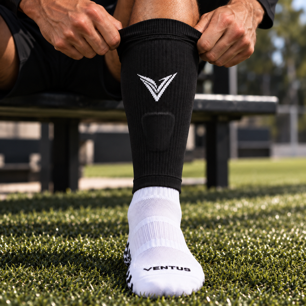 Player pulling a black Pro-Cut Sleeve up over a white Pro-Grip Sock on the pitch