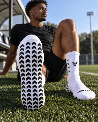 Player sitting on the pitch showing the silicone grip pattern on the sole of Pro-Grip Socks